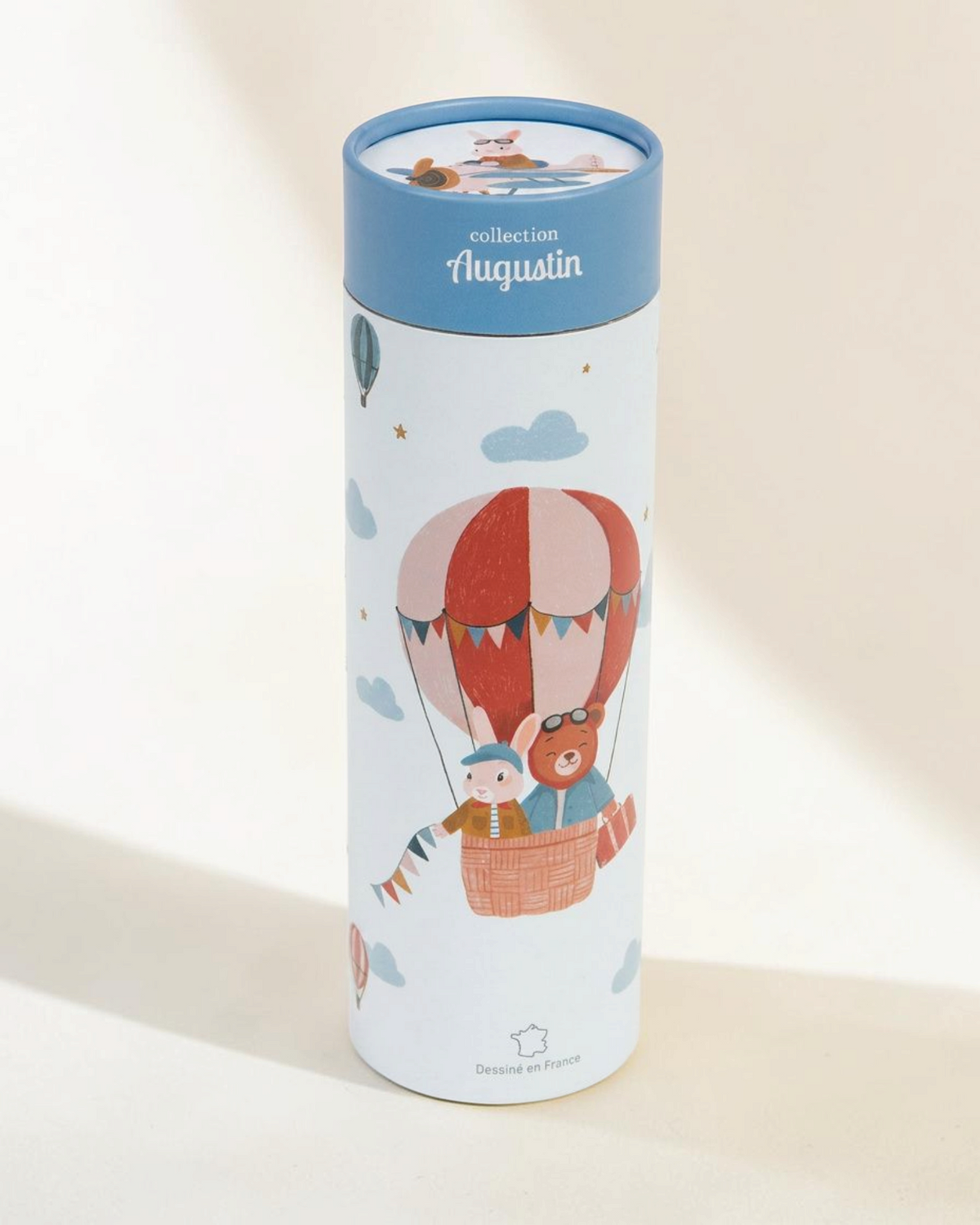 Sprall mätsticka för barn i en rund förpackning med motiv av luftballonger och djur i roströda och blå toner.